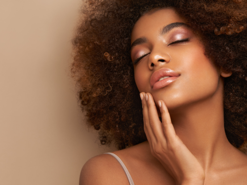 Femme afro-américaine aux cheveux frisés touchant son visage